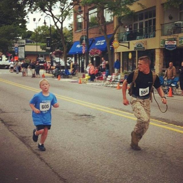 Զինվորականը վազում է տղայի կողքով, ով մարաթոնի ժամանակ հետ է մնացել խմբից